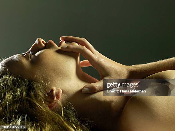 naked young woman lying on floor, eyes closed, finger pulling on lip - vorspiel stock-fotos und bilder