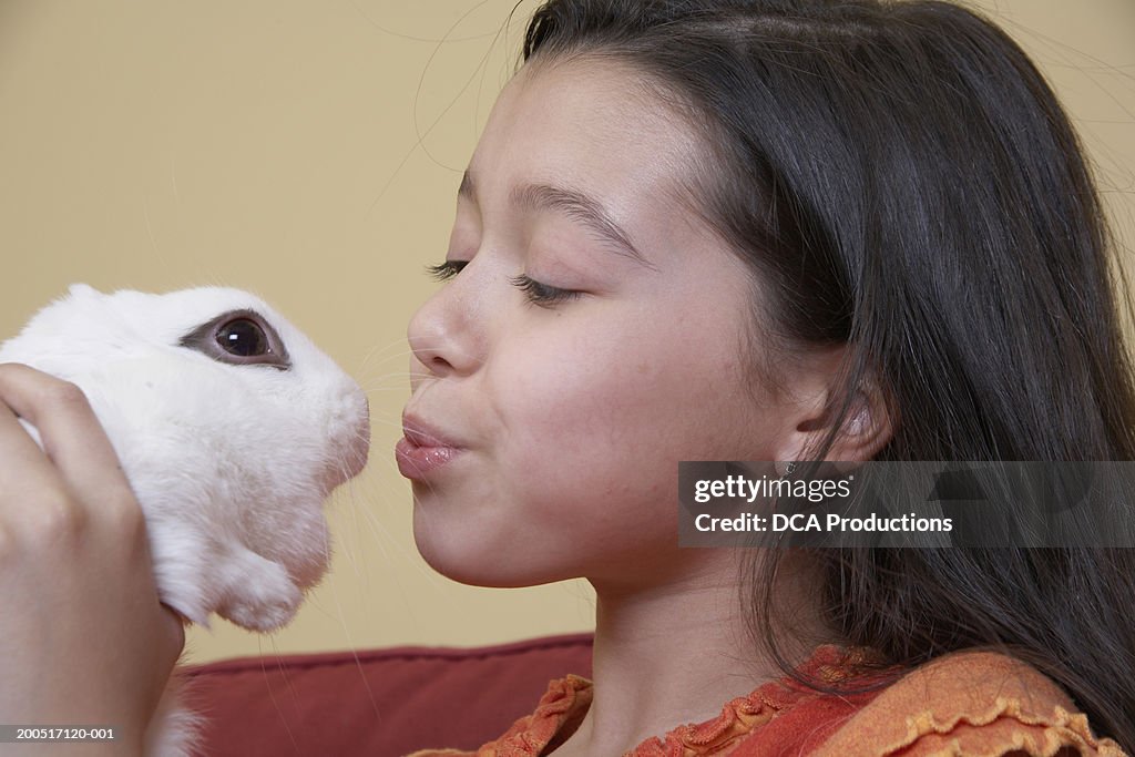 Girl (10-12) holding rabbit, close-up, side view