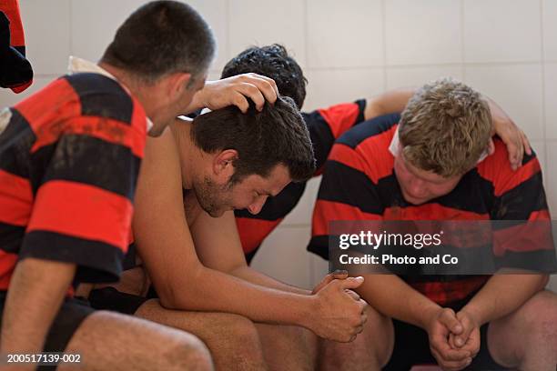 rugby players sitting with heads bowed in dressing room - althete fotografías e imágenes de stock