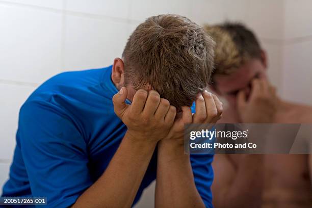 rugby player sitting in changing room covering face with shirt - young boys changing in locker room stock pictures, royalty-free photos & images