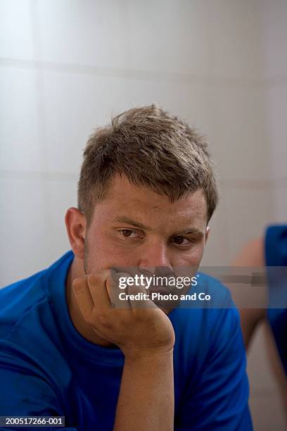 rugby player sitting in changing room resting chin on hand - young boys changing in locker room imagens e fotografias de stock