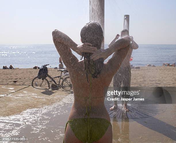 young woman, in green bikini, showering near beach, rear view - shower man woman washing stock pictures, royalty-free photos & images