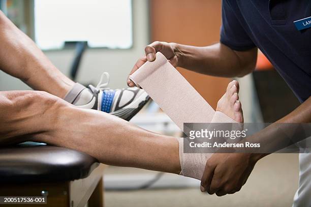 physical therapist wrapping mature man's foot in bandage, side view - caviglia foto e immagini stock