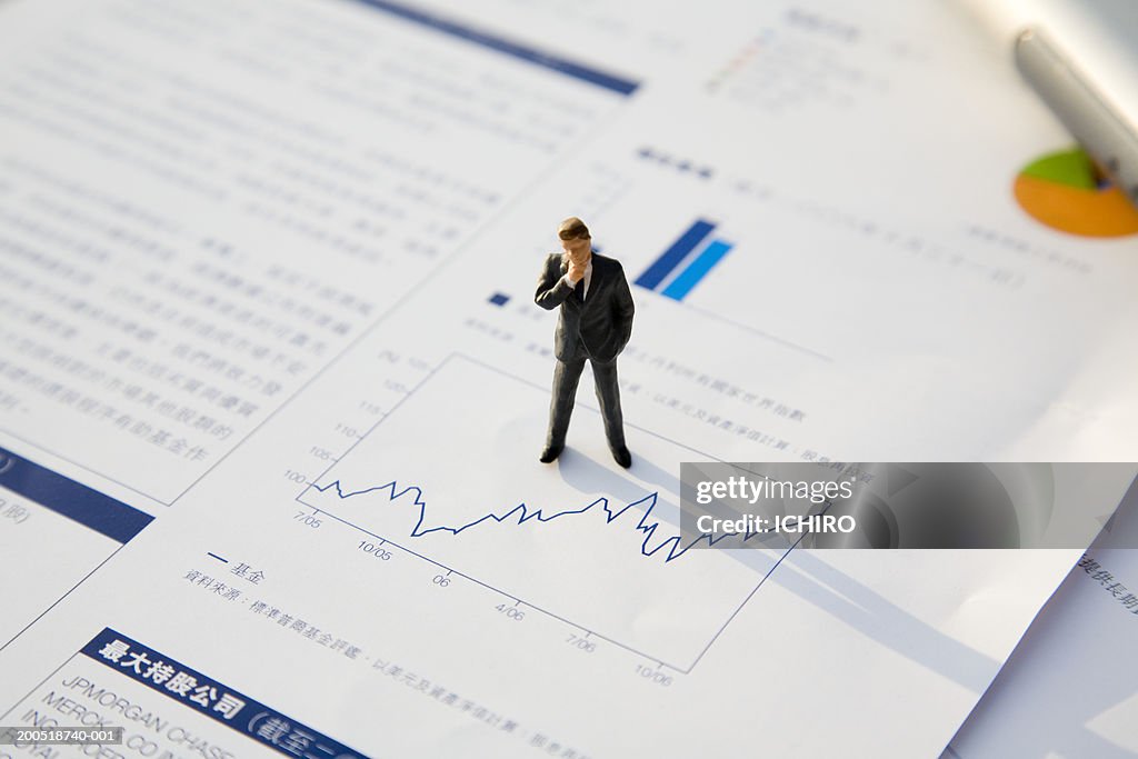 Businessman figurine atop line graph, elevated view