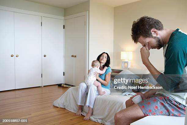 parents and baby girl (9-12 months) in bedroom, man holding head - tired mum stock pictures, royalty-free photos & images