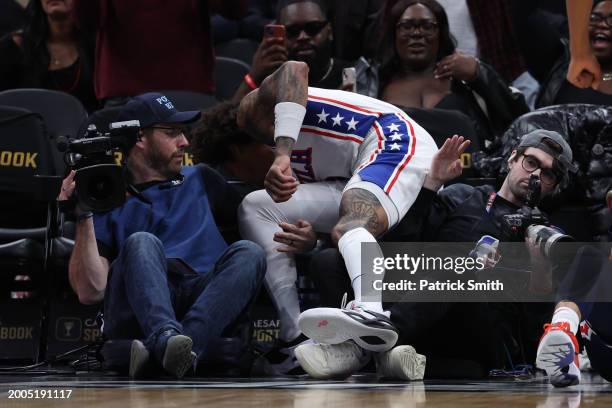 Kelly Oubre Jr. #9 of the Philadelphia 76ers collides with a videographer and photographer against the Washington Wizards at Capital One Arena on...