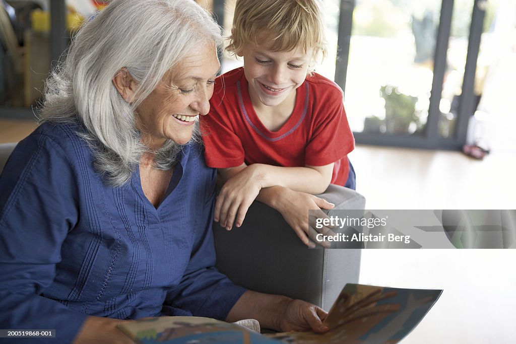Grandmother and grandson (5-7) reading book, smiling