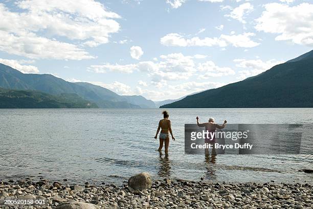 two women walking into lake - slocan lake stock pictures, royalty-free photos & images