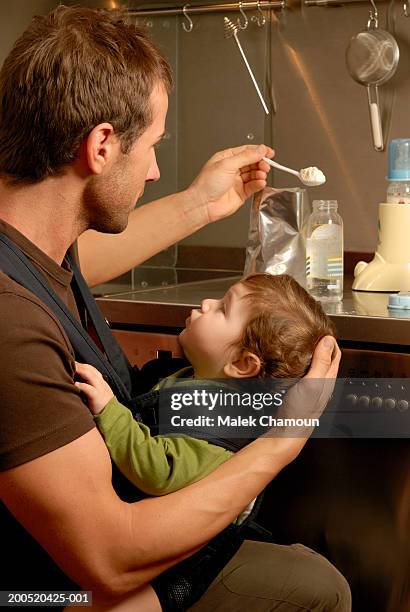 father carrying baby son (7-9 months) while preparing milk in kitchen - baby powder fotografías e imágenes de stock