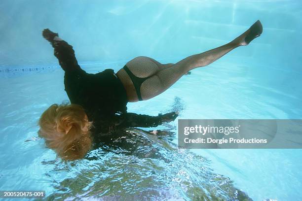 woman in pool, wearing high heels and stockings, underwater view - thong stock-fotos und bilder