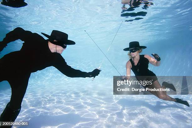 couple fencing in pool, wearing hats and masks, underwater view - mask confrontation stock pictures, royalty-free photos & images