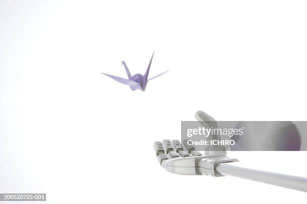 robotic arm reaching for origami crane - origami a forma di gru foto e immagini stock