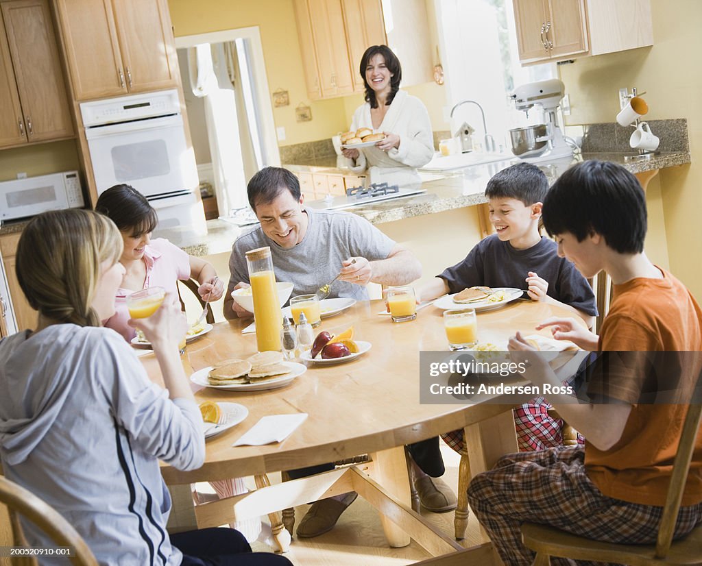 Mother and father eating breakfast with four children (9-17)