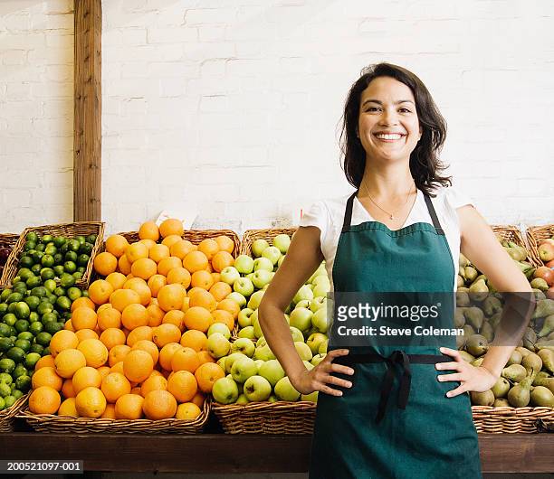 female greengrocer at market stall, smiling, portrait - schürze stock-fotos und bilder