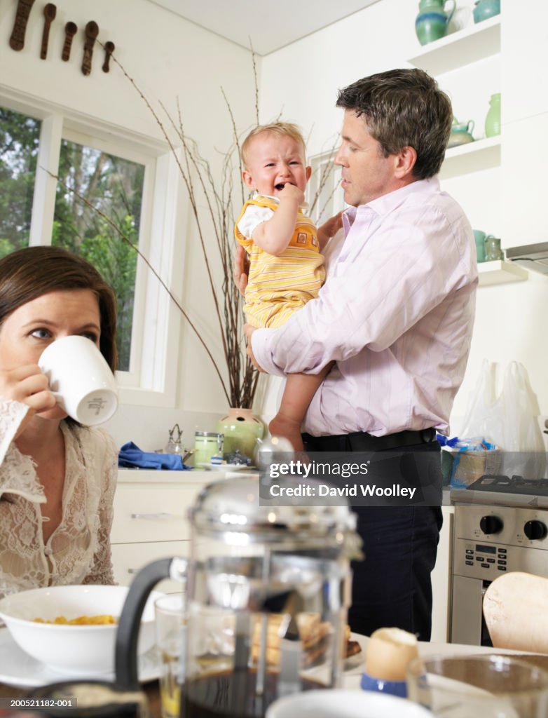 Couple in kitchen, father holding crying baby daughter (3-6 months)