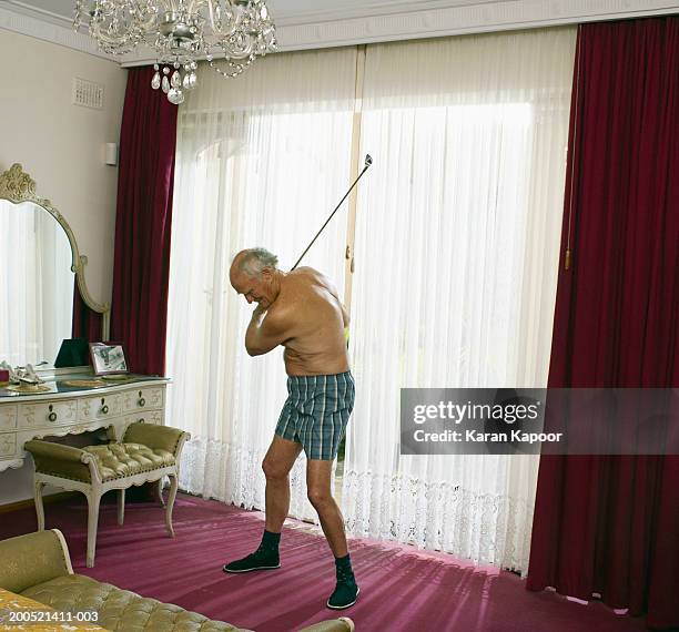 senior man swinging golf club in bedroom, wearing boxer shorts - active seniors golf stock pictures, royalty-free photos & images
