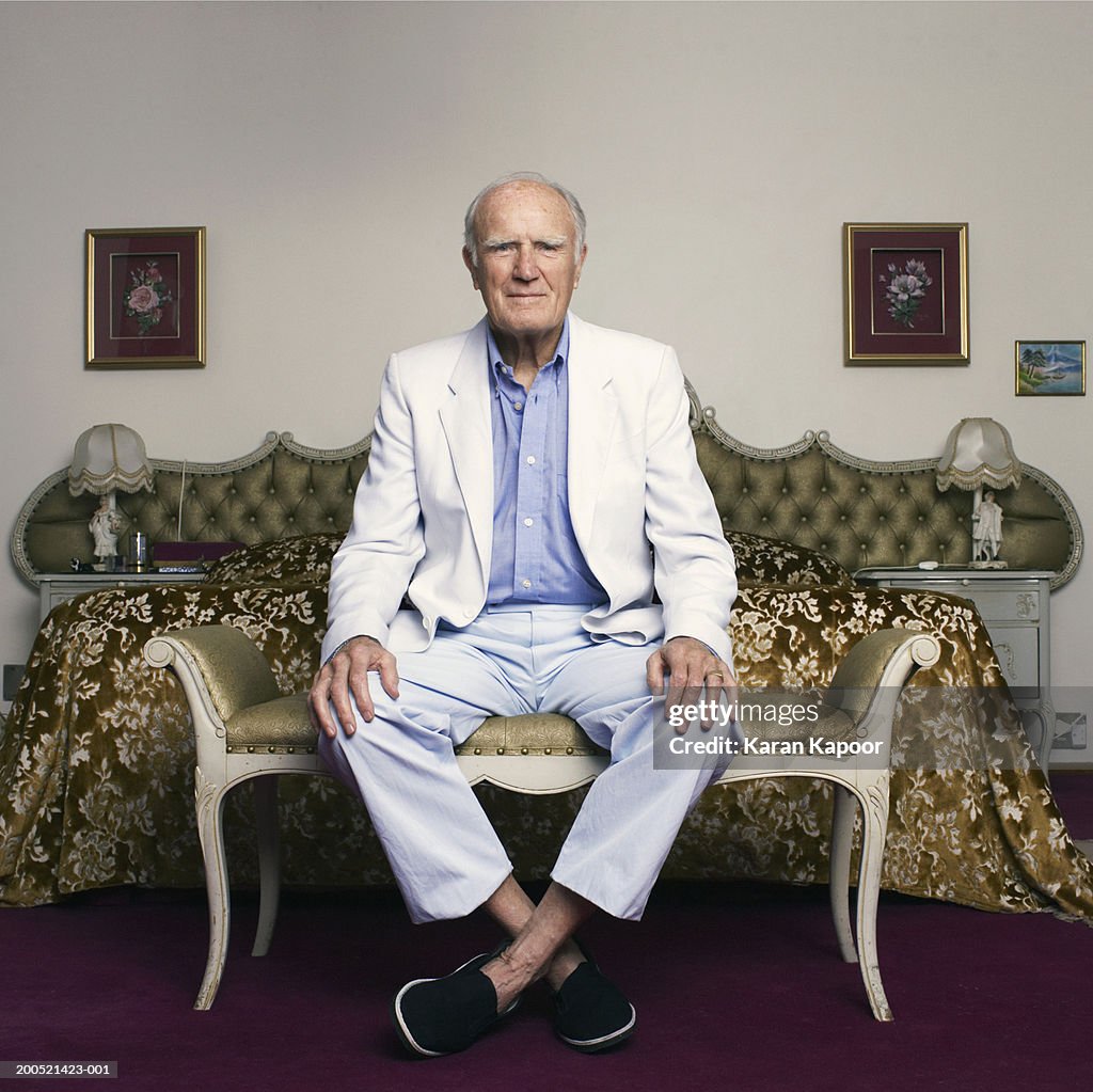 Senior man sitting on chair in bedroom, portrait