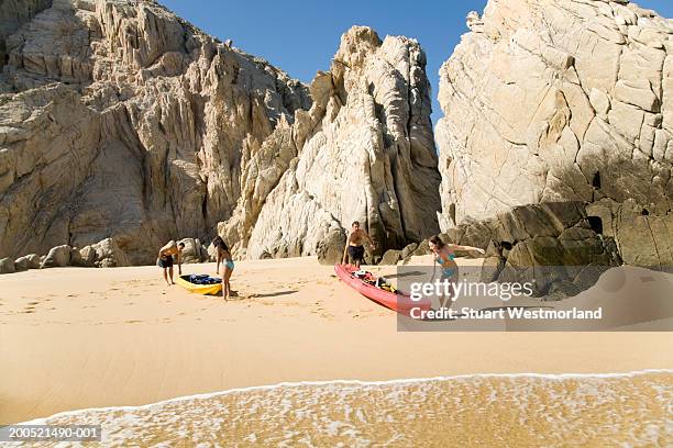 "mexico, baja, land's end, four adults with kayaks on beach" - cabo san lucas fotografías e imágenes de stock