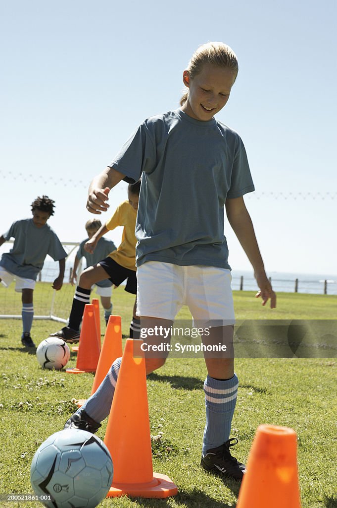 Children (9-12) practicing dribbling soccer ball
