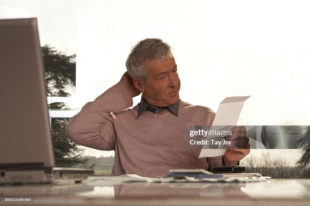 Man sitting at desk scratching head