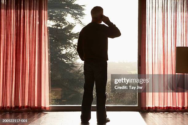 man using mobile phone, looking through window - onherkenbaar persoon stockfoto's en -beelden