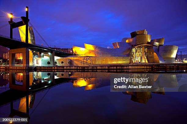 spain, bilbao, gugenheim museum and bridge, illuminated at dusk - bilbao fotografías e imágenes de stock