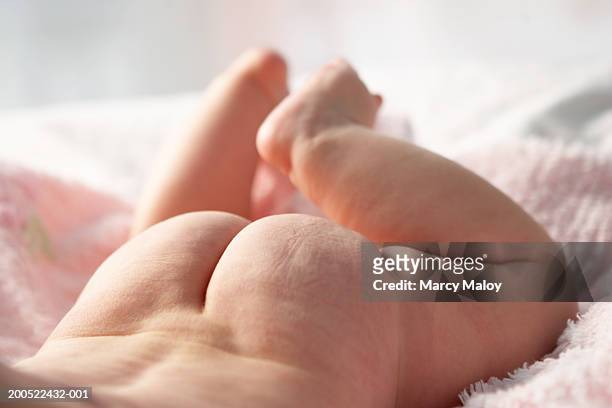 naked baby girl (3-6 months) lying on bed, low section - cute bums stockfoto's en -beelden