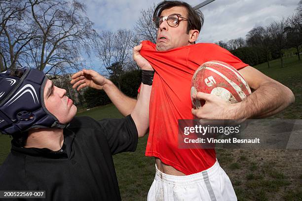 man wearing spectacles grabbed by rugby player - rugby tackle stockfoto's en -beelden