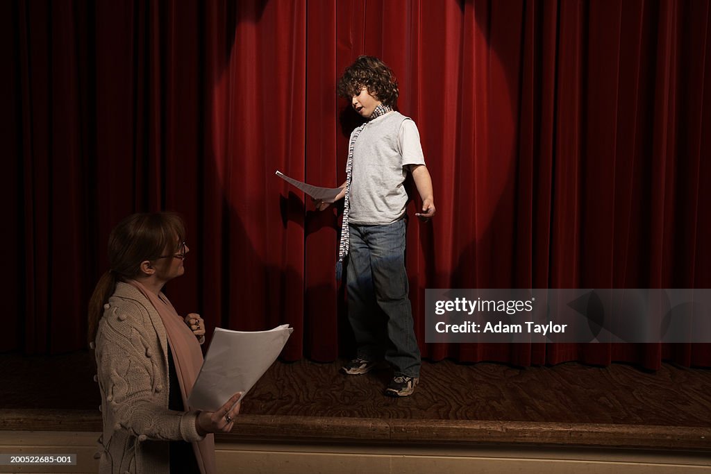 Female teacher and boy (10-12) standing on stage rehearsing