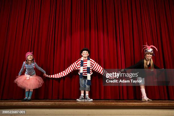 two girls and boy (6-10) in costume taking bow on stage, smiling - bowing stock pictures, royalty-free photos & images