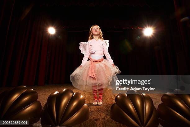 girl (6-10) in fairy costume standing on stage, looking up, smiling - child on stage stock-fotos und bilder