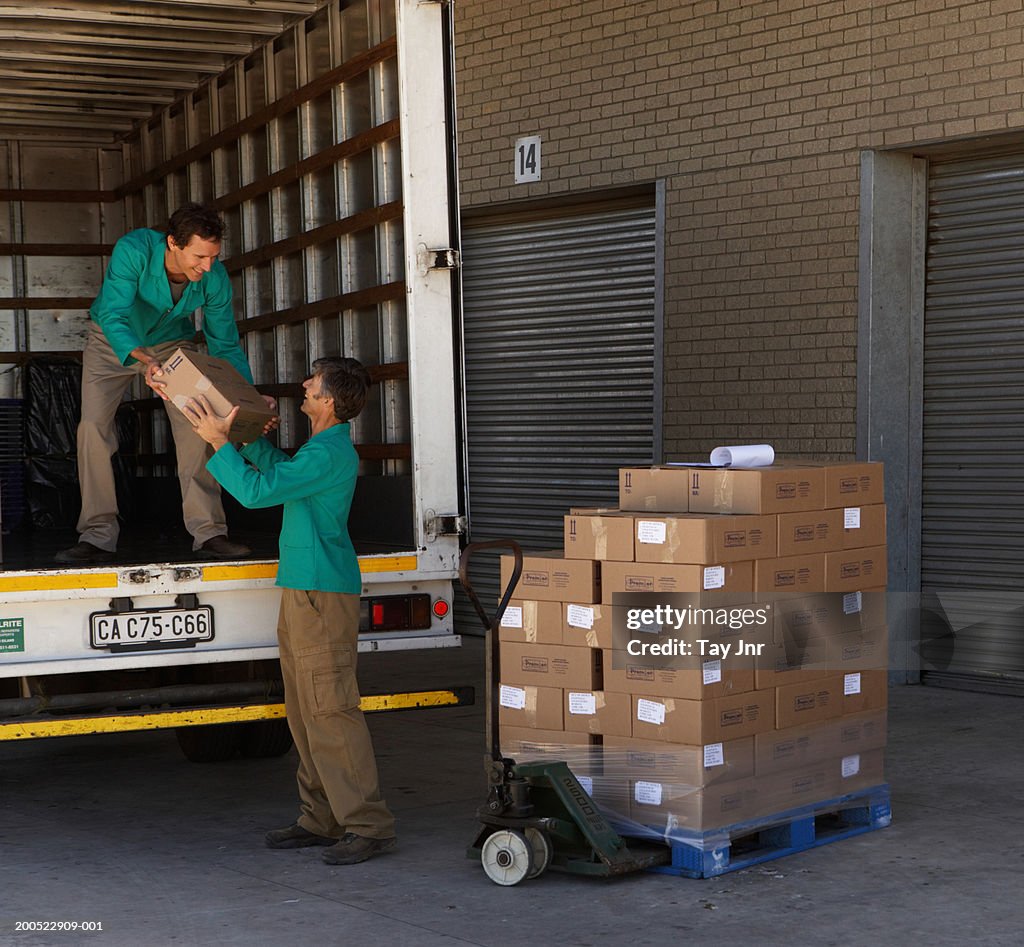 Two men loading boxes into lorry from pallet