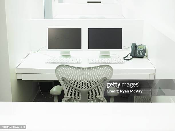 two computers and phone atop desk in office - cubicle stock pictures, royalty-free photos & images