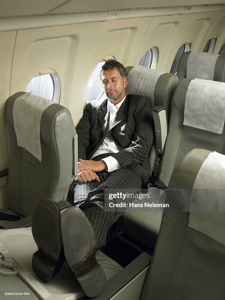 Businessman sleeping with feet up in aero plane