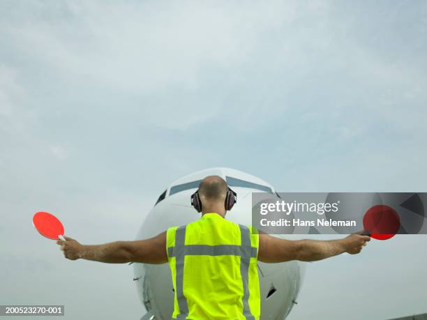 technician signalling directions to aero plane - regeln stock-fotos und bilder