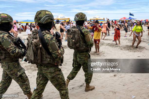 Soldiers patrol past revelers during Carnival celebrations on February 11, 2024 in Atacames, Ecuador. Violent crime has dropped nationwide in the...