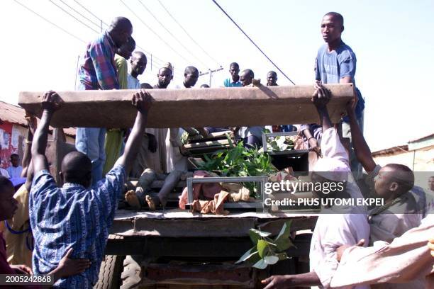 People gather on a truck conveying eight bodies for burial at Kabala Doki in Kaduna 22 November 2002. More than hundred of people have died following...