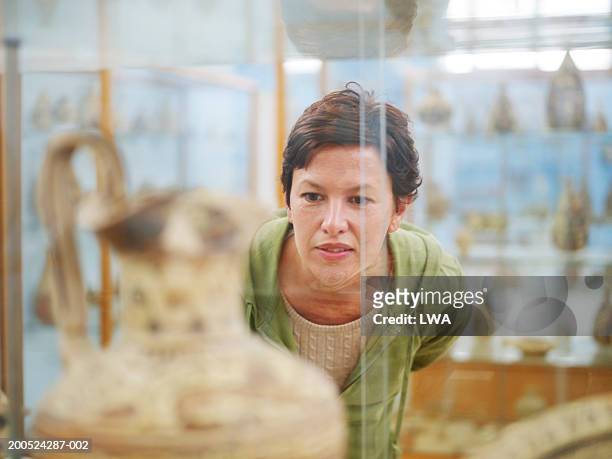 woman looking at ancient vase in display case - delos stock-fotos und bilder