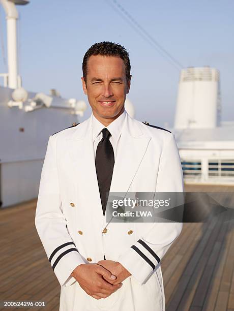 officer standing on deck of cruise ship, smiling - bootskapitän stock-fotos und bilder