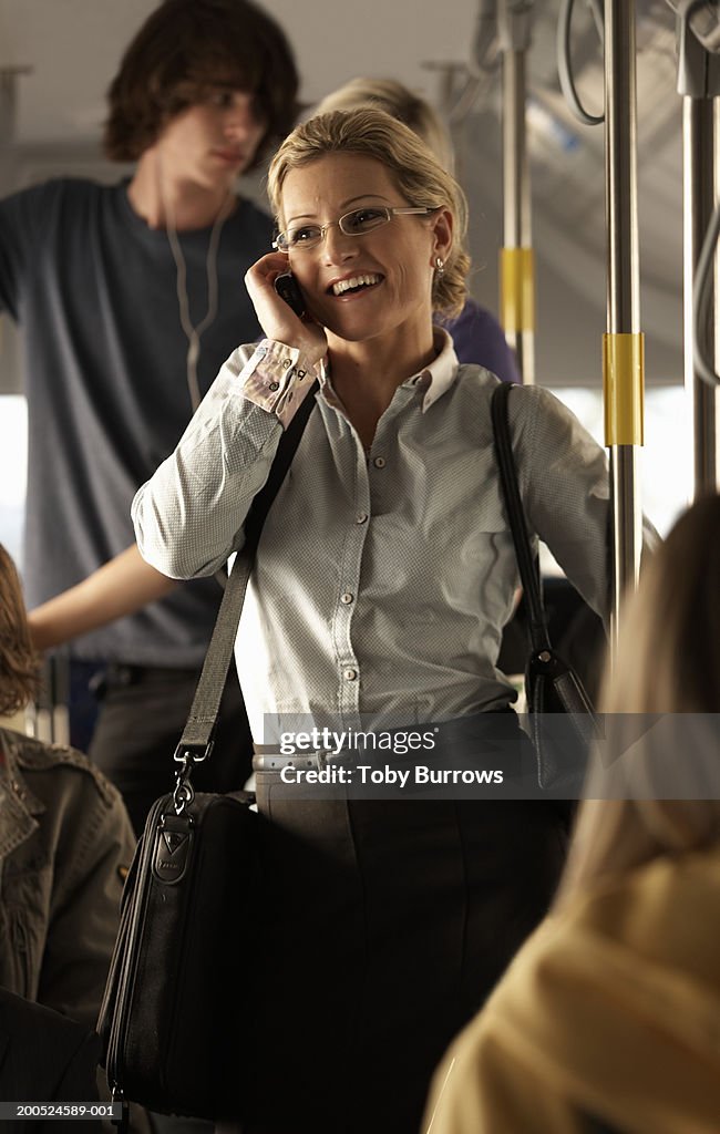 Woman using mobile phone on bus, smiling