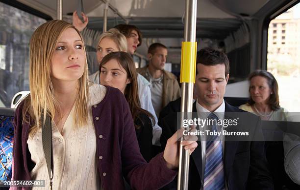 young woman holding railing on bus - crowded bus stock pictures, royalty-free photos & images