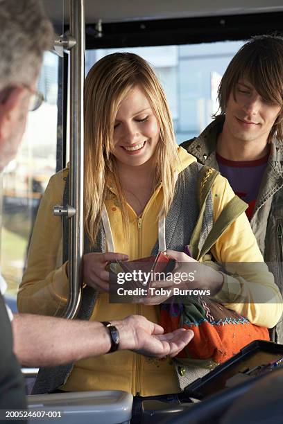 young woman paying bus fare to driver, smiling - fare stockfoto's en -beelden