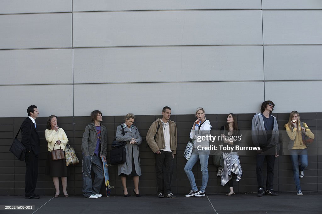 Group of people waiting against wall