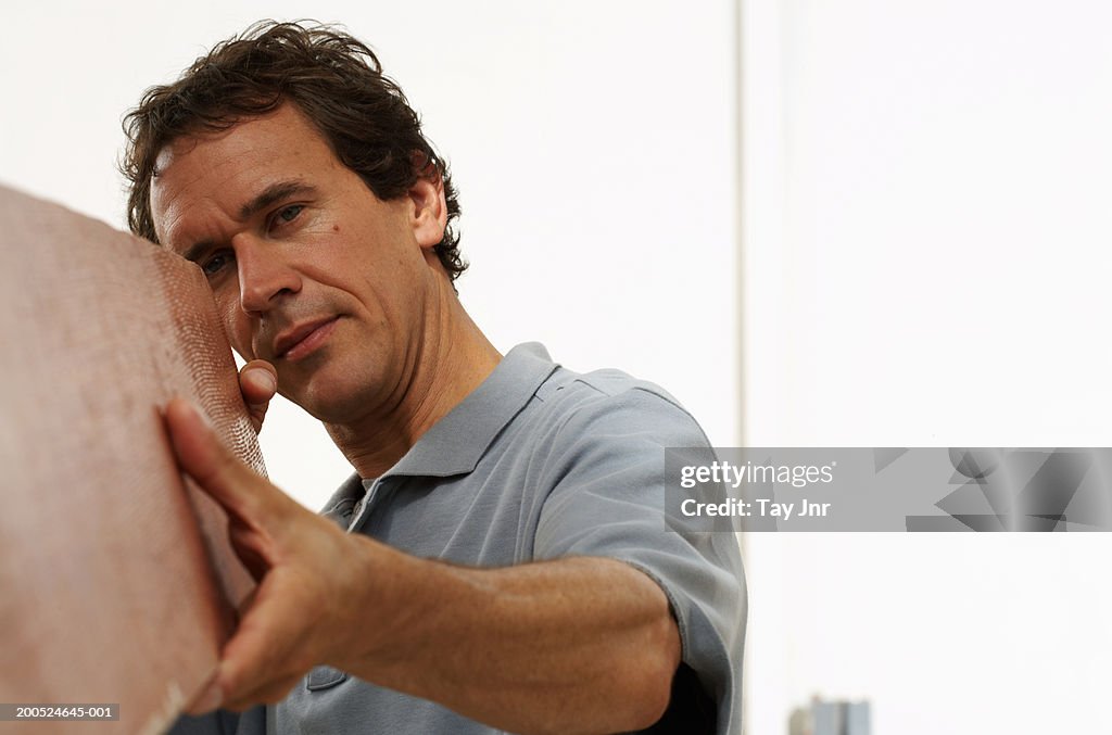 Man looking at wood in boat building workshop, close-up