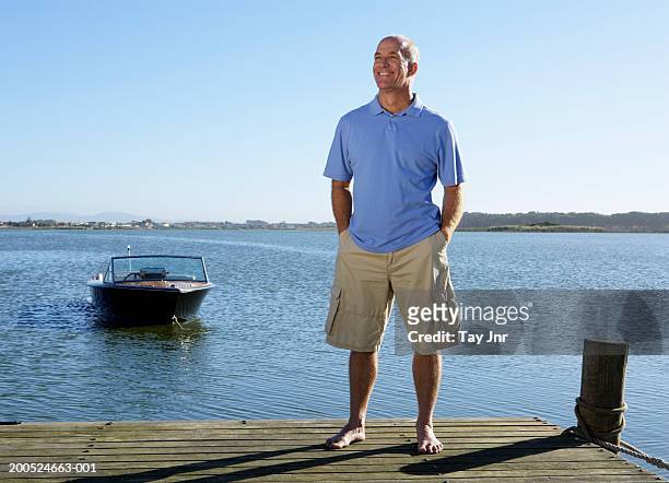 mature man standing on jetty, smiling - blue shorts stock pictures, royalty-free photos & images