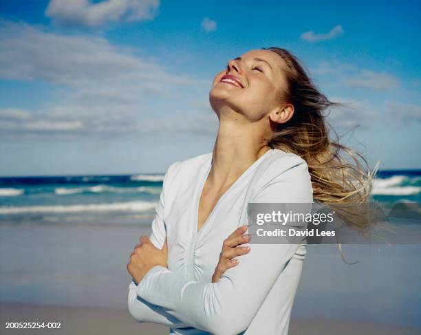 woman standing on beach, arms folded, head back, smiling - young woman beach smiling stock pictures, royalty-free photos & images