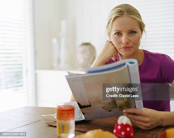 woman holding magazine at table, portrait - magazines stockfoto's en -beelden