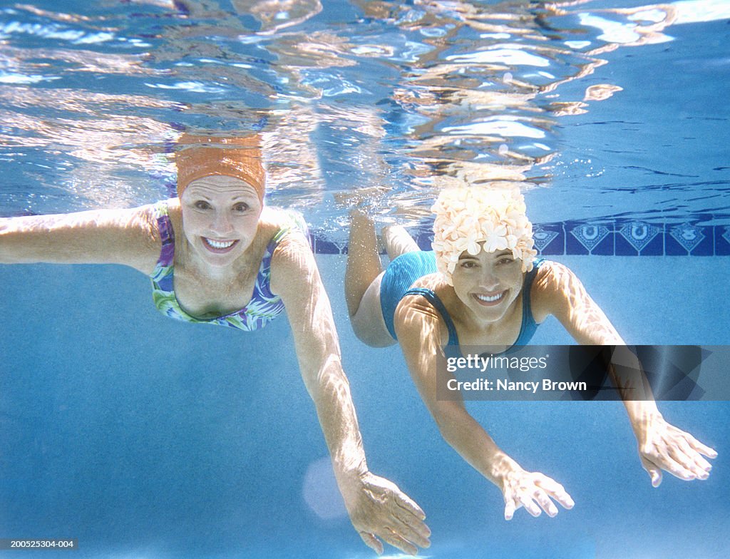 Women swimming, smiling, portrait, underwater view