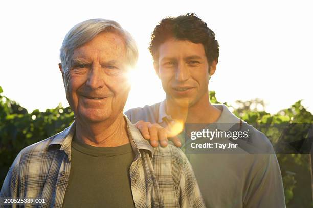 senior father and mature son standing in vineyard, smiling, portrait - continuity fotografías e imágenes de stock