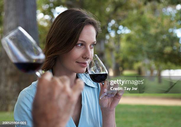 young woman smelling bouquet of wine at tasting in garden, smiling - wijn proeven stockfoto's en -beelden